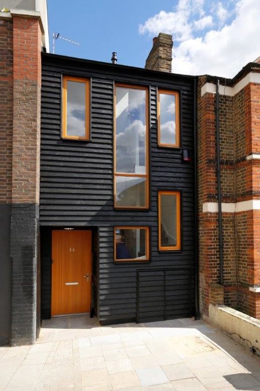 Ispirazione per la facciata di una casa a schiera nera contemporanea a due piani con rivestimento in legno