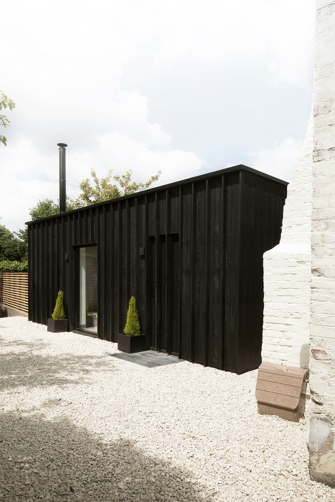 Пример оригинального дизайна: маленький, одноэтажный, деревянный, черный частный загородный дом в современном стиле с плоской крышей и крышей из смешанных материалов для на участке и в саду