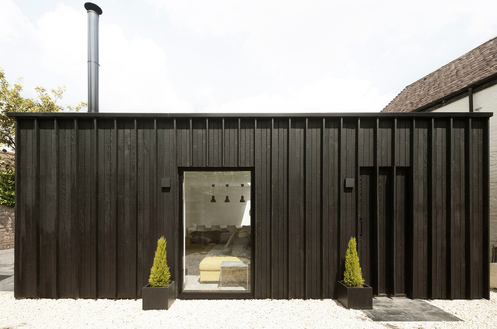 Idées déco pour une petite façade de maison noire contemporaine en bois de plain-pied avec un toit plat et un toit mixte.