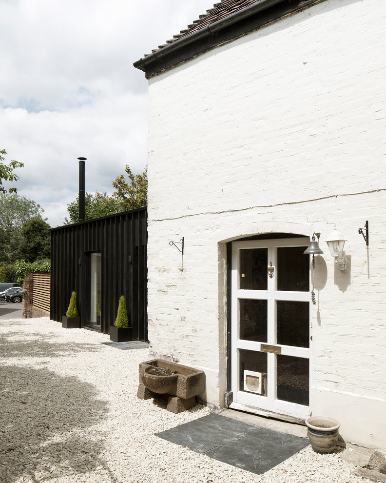 Kleines, Einstöckiges Modernes Haus mit schwarzer Fassadenfarbe, Flachdach und Misch-Dachdeckung in Hampshire