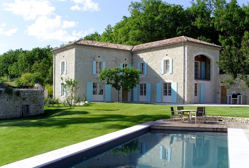 Пример оригинального дизайна: двухэтажный дом в средиземноморском стиле с облицовкой из камня и вальмовой крышей