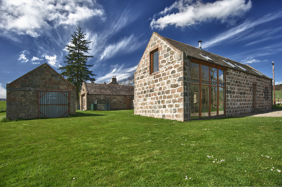 Cette image montre une grande façade de maison traditionnelle en pierre à un étage avec un toit à deux pans.
