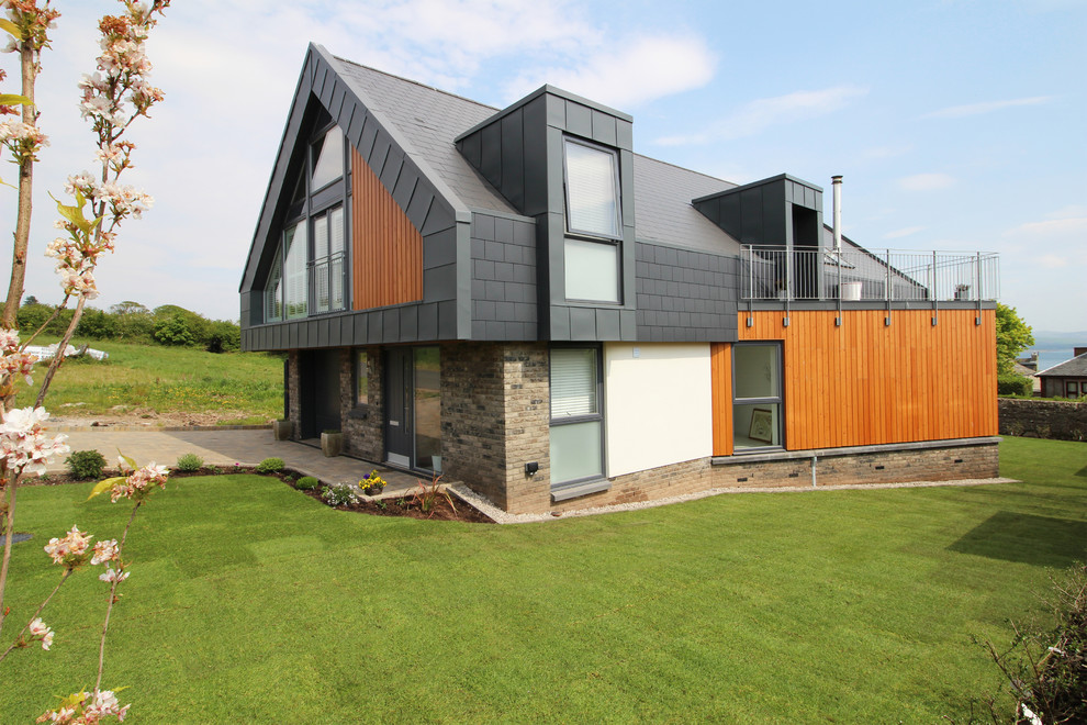 Photo of a medium sized and multi-coloured contemporary two floor detached house in Glasgow with wood cladding, a pitched roof and a tiled roof.