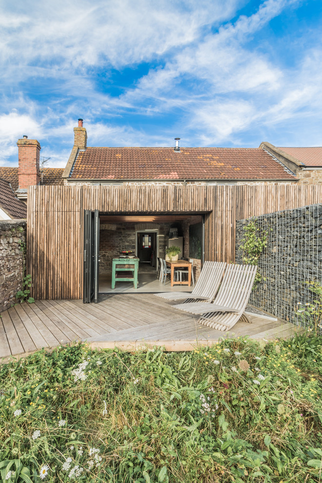 Kleine, Einstöckige Landhausstil Holzfassade Haus mit brauner Fassadenfarbe und Flachdach in Sonstige