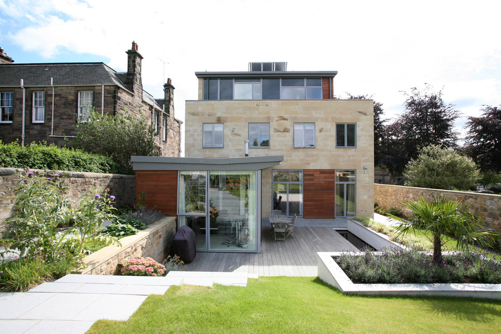 This is an example of a medium sized contemporary house exterior in Edinburgh with three floors, stone cladding and a flat roof.