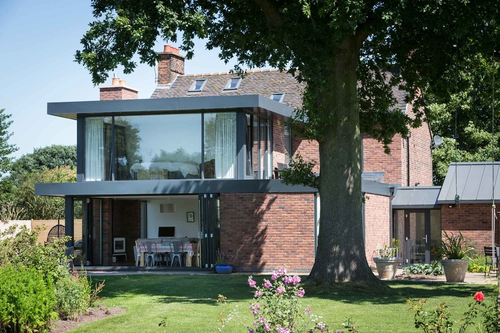 This is an example of a medium sized and brown contemporary two floor brick house exterior in West Midlands with a pitched roof.