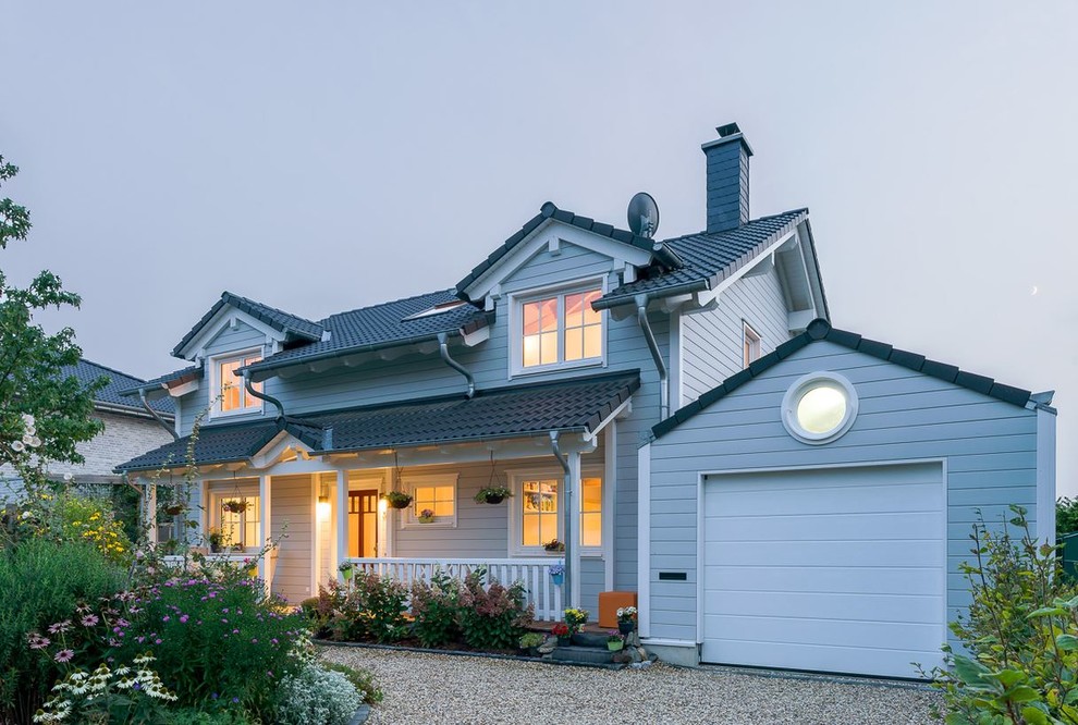 Cette photo montre une façade de maison grise nature en bois de taille moyenne et à un étage avec un toit à deux pans et un toit en tuile.