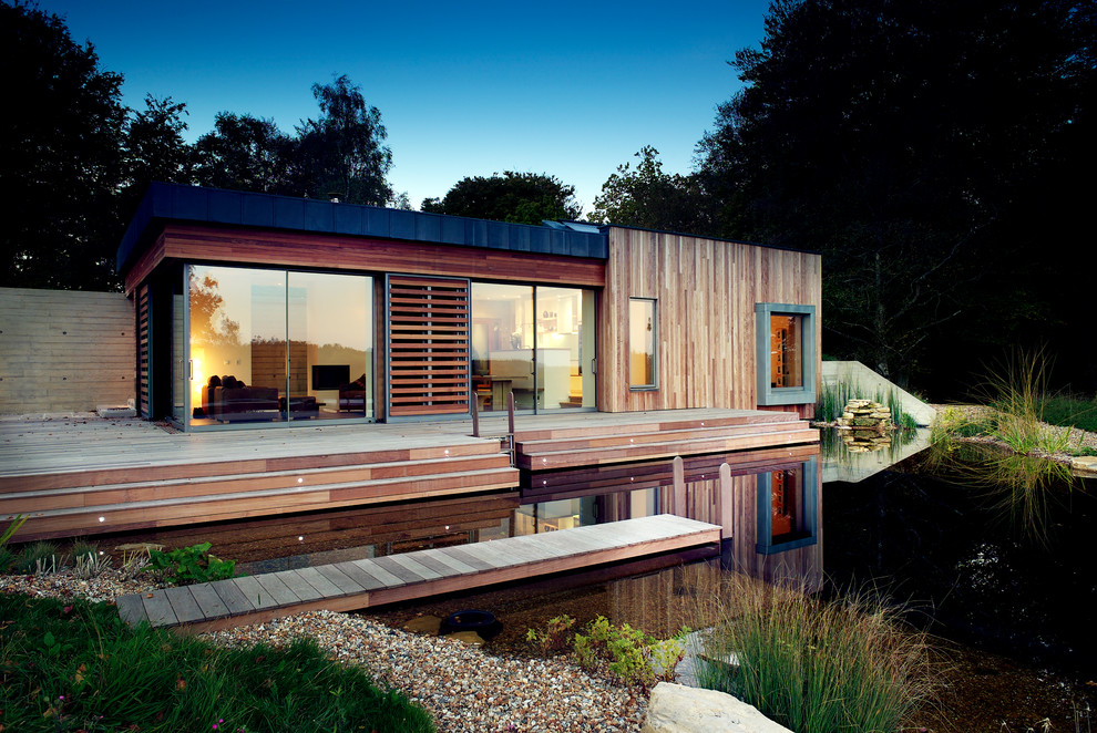 This is an example of a medium sized modern bungalow house exterior in Hampshire with wood cladding.