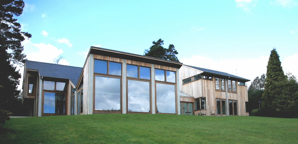 Immagine della facciata di una casa grande marrone contemporanea a due piani con rivestimento in legno e tetto a capanna