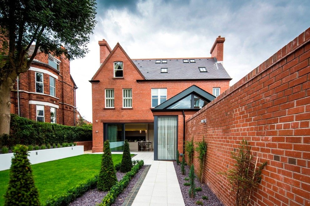 Large transitional red three-story brick gable roof photo in London