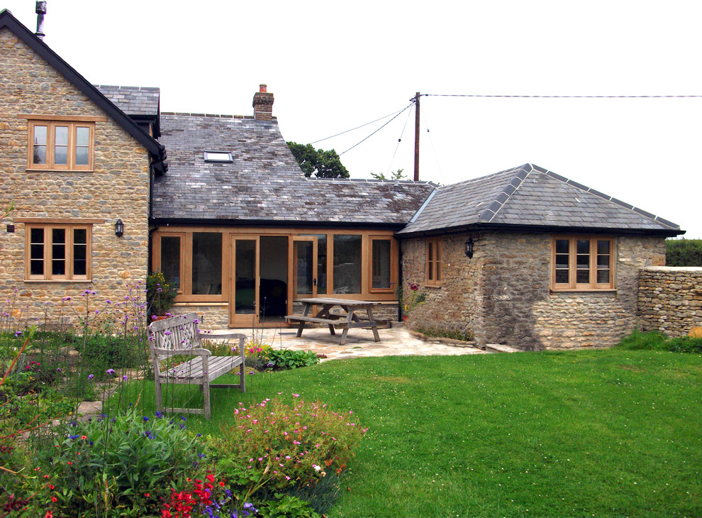 Foto de fachada beige de estilo de casa de campo de tamaño medio de dos plantas con revestimiento de piedra y tejado a dos aguas