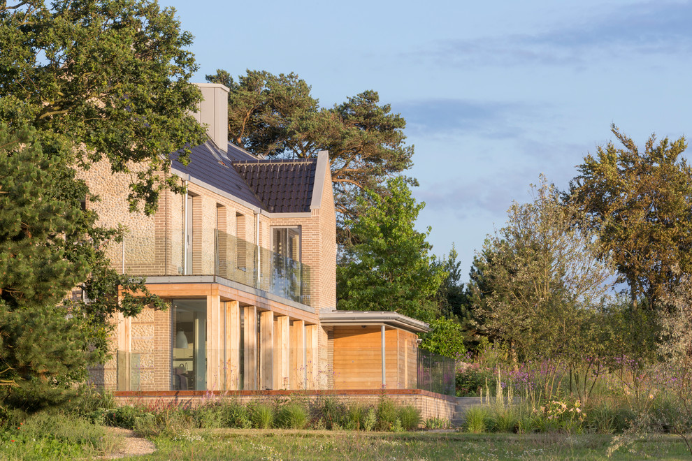 Diseño de fachada de casa campestre grande de dos plantas con revestimiento de piedra, tejado a dos aguas y tejado de teja de barro
