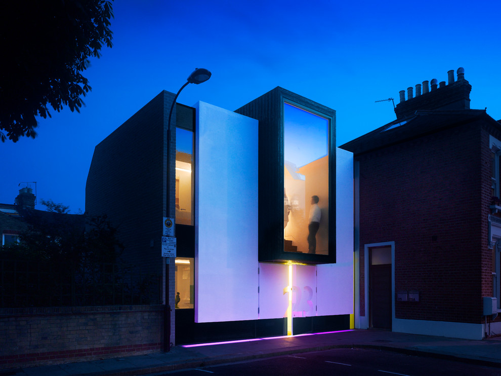 This is an example of a medium sized and white contemporary render house exterior in London with three floors.