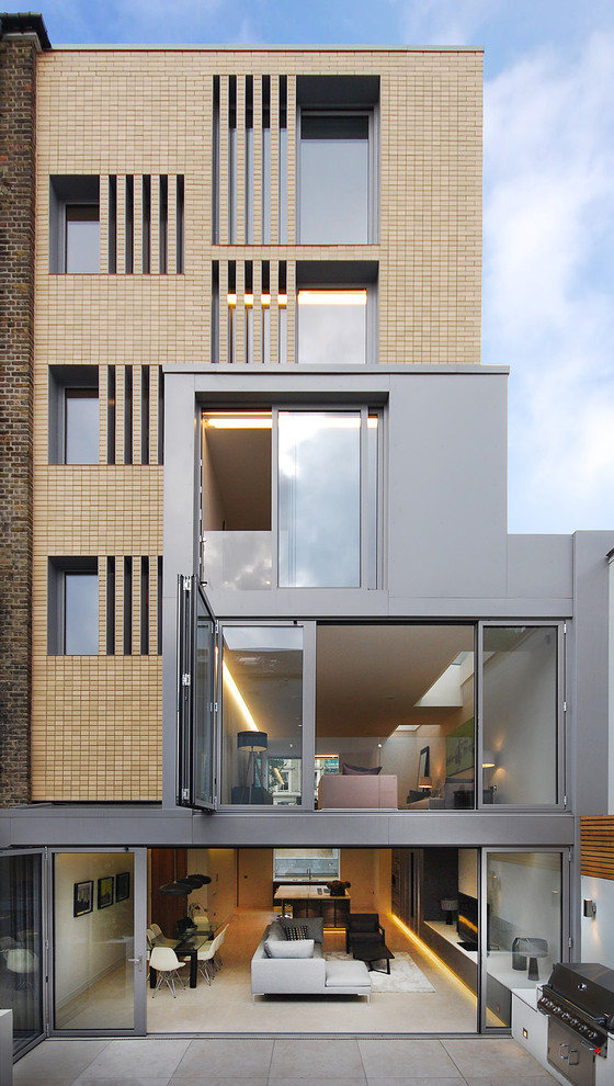 Large and brown contemporary brick house exterior in London with three floors and a flat roof.