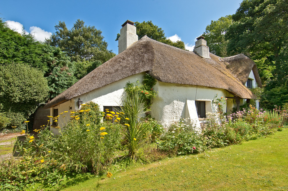 На фото: маленький, двухэтажный дом с облицовкой из цементной штукатурки для на участке и в саду