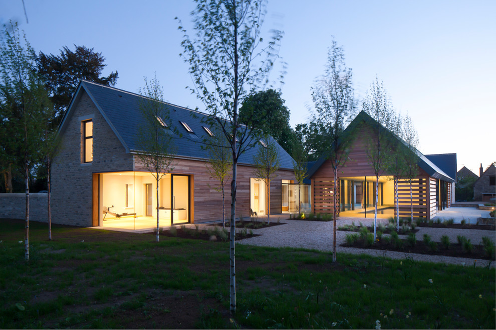Идея дизайна: большой, двухэтажный, коричневый частный загородный дом в современном стиле с двускатной крышей, комбинированной облицовкой и крышей из гибкой черепицы