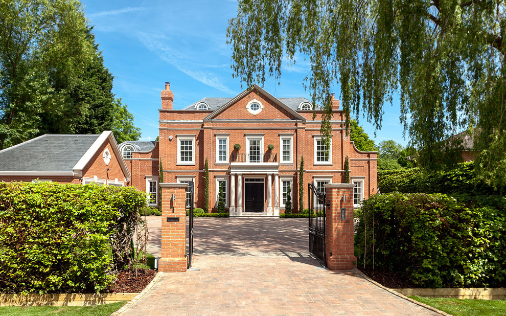Photo of a red traditional brick house exterior in Surrey with three floors.