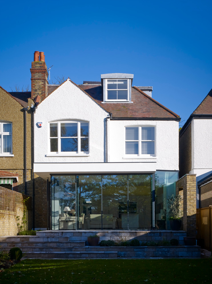 Large minimalist white three-story stucco exterior home photo in London with a clipped gable roof