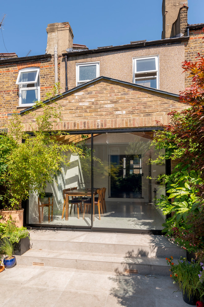 Small danish one-story brick exterior home photo in London with a tile roof