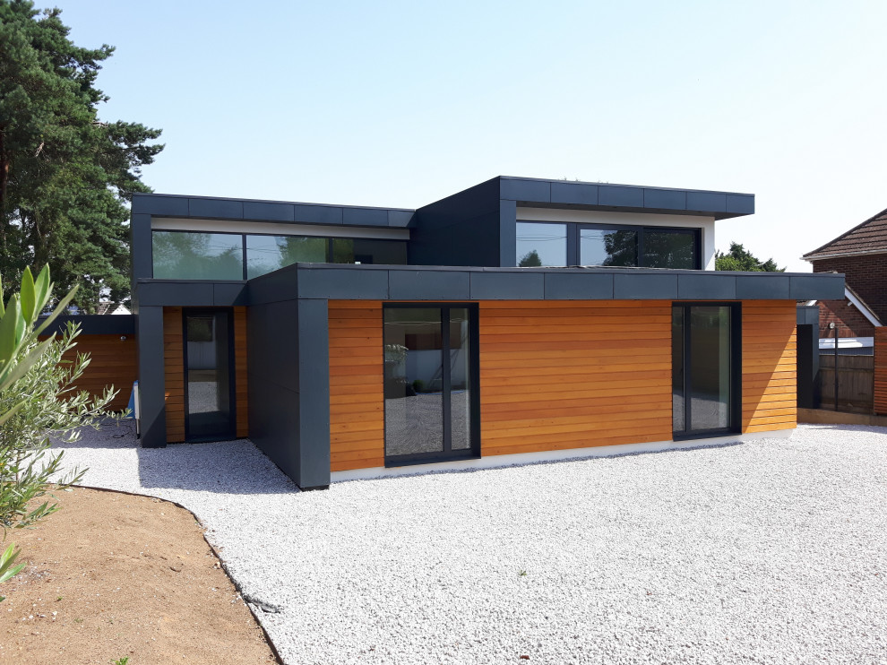 Idées déco pour une façade de maison multicolore contemporaine en planches et couvre-joints à un étage avec un revêtement mixte, un toit plat, un toit mixte et un toit gris.