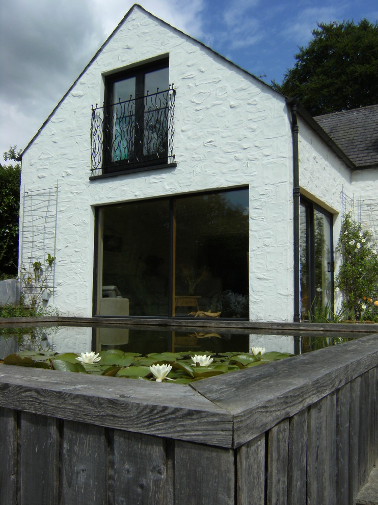 Modelo de fachada blanca de estilo de casa de campo pequeña de dos plantas con revestimiento de estuco