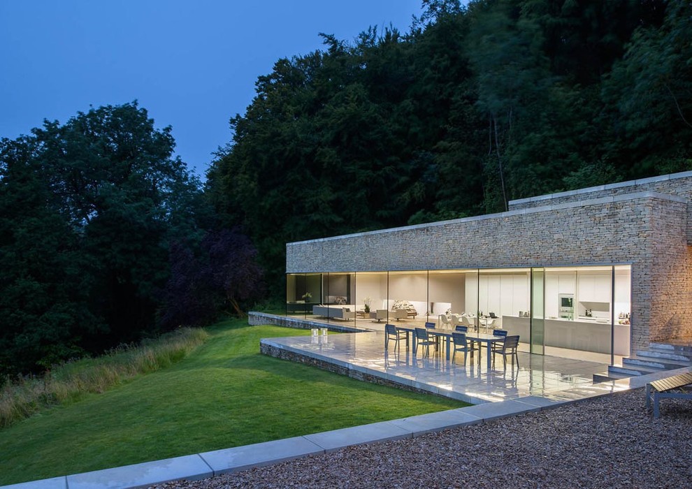 Réalisation d'une façade de maison beige minimaliste en pierre de plain-pied.