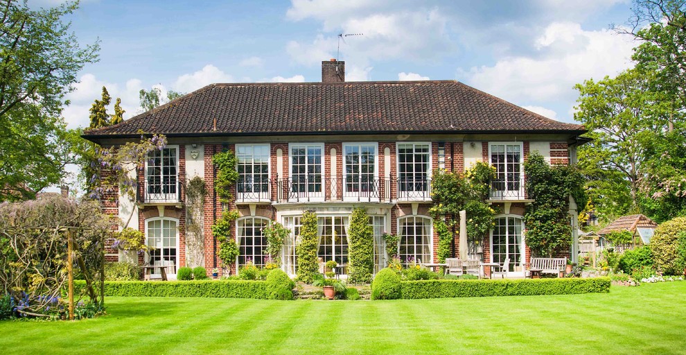 Zweistöckiges Klassisches Haus mit roter Fassadenfarbe, Backsteinfassade und Walmdach in Surrey