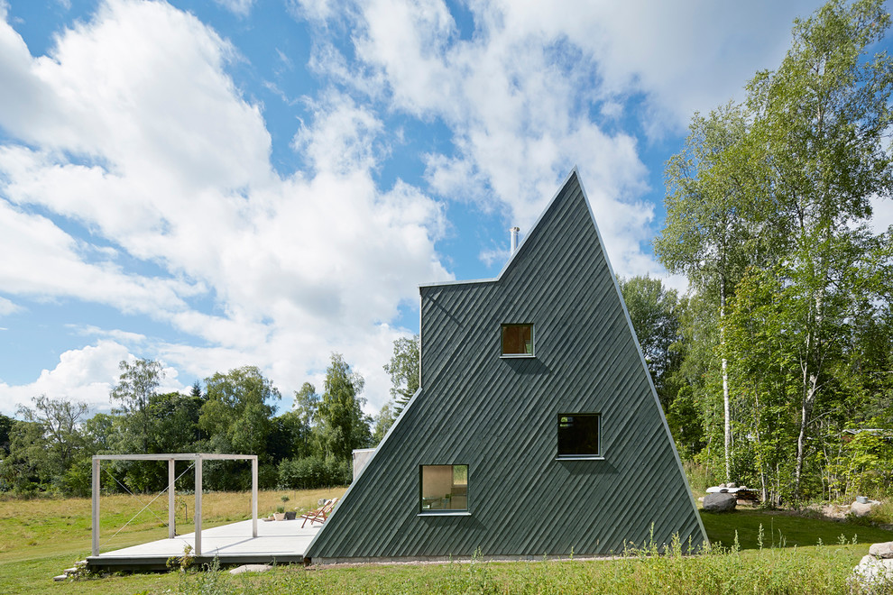 На фото: большой, трехэтажный, деревянный, серый дом в скандинавском стиле с двускатной крышей