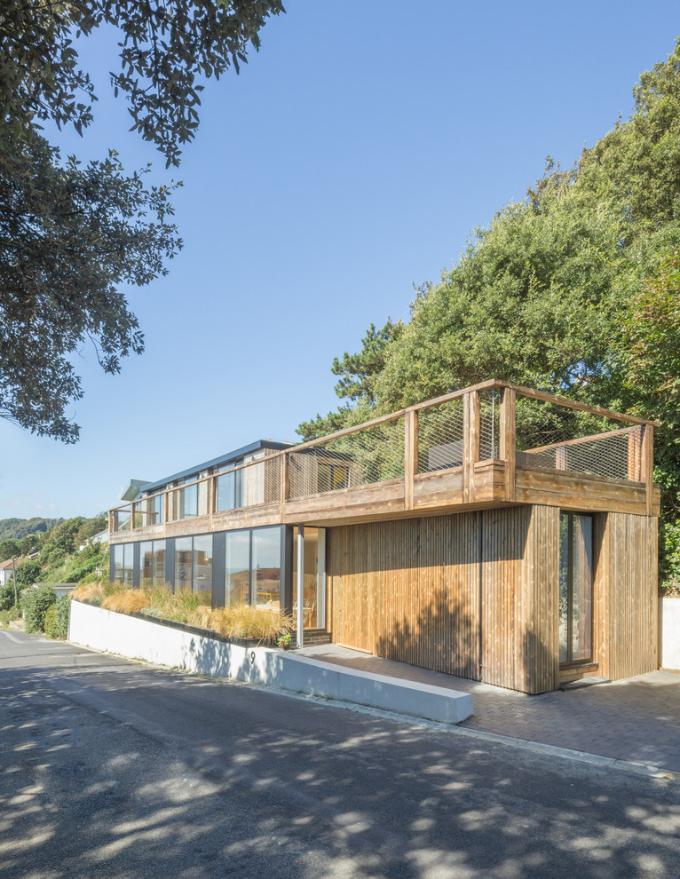 Diseño de fachada de casa beige contemporánea de tamaño medio de dos plantas con revestimiento de madera y tejado plano