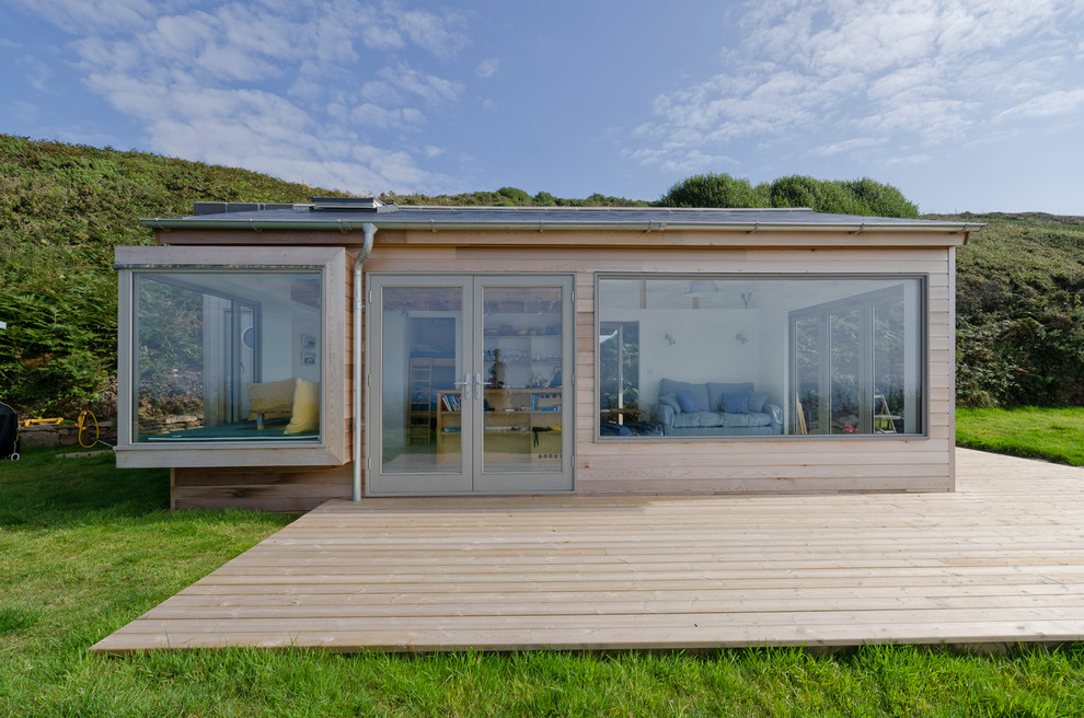 Photo of a small and beige contemporary bungalow detached house in Cornwall with wood cladding and a flat roof.