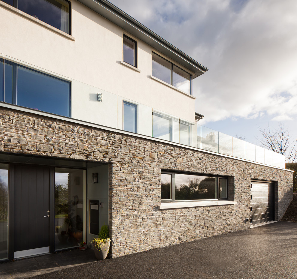 Design ideas for an expansive contemporary house exterior in Belfast with three floors and stone cladding.