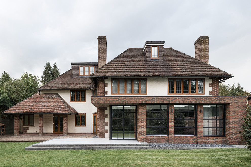 Idée de décoration pour une façade de maison multicolore tradition en brique à un étage avec un toit à croupette.