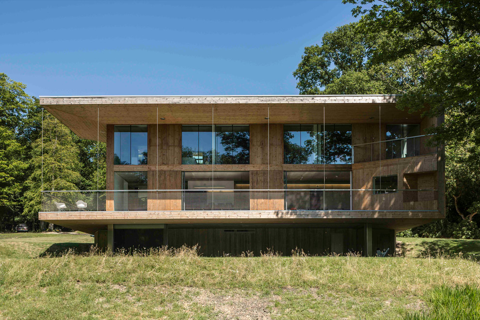 Idée de décoration pour une grande façade de maison marron design en bois à deux étages et plus avec un toit plat.