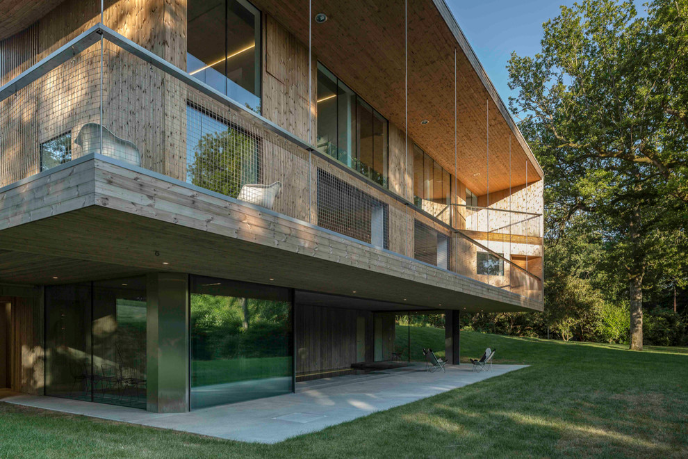 Стильный дизайн: большой, трехэтажный, деревянный, коричневый дом в современном стиле с плоской крышей - последний тренд