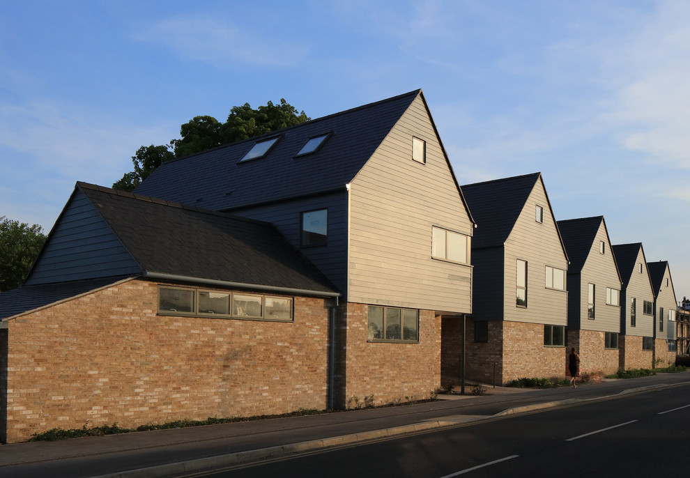 Photo of a medium sized and gey contemporary detached house in Cambridgeshire with three floors, wood cladding, a pitched roof and a tiled roof.