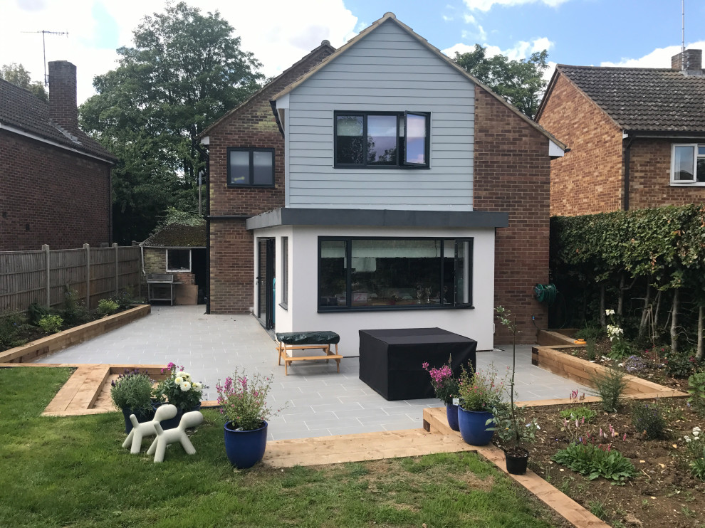 Medium sized and gey contemporary two floor detached house in Hertfordshire with concrete fibreboard cladding, a pitched roof and a tiled roof.