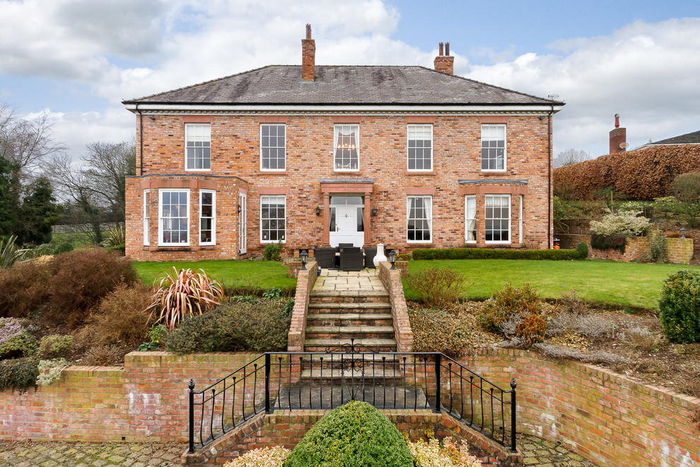 Klassisches Einfamilienhaus mit Backsteinfassade, roter Fassadenfarbe, Walmdach und Schindeldach in Cheshire