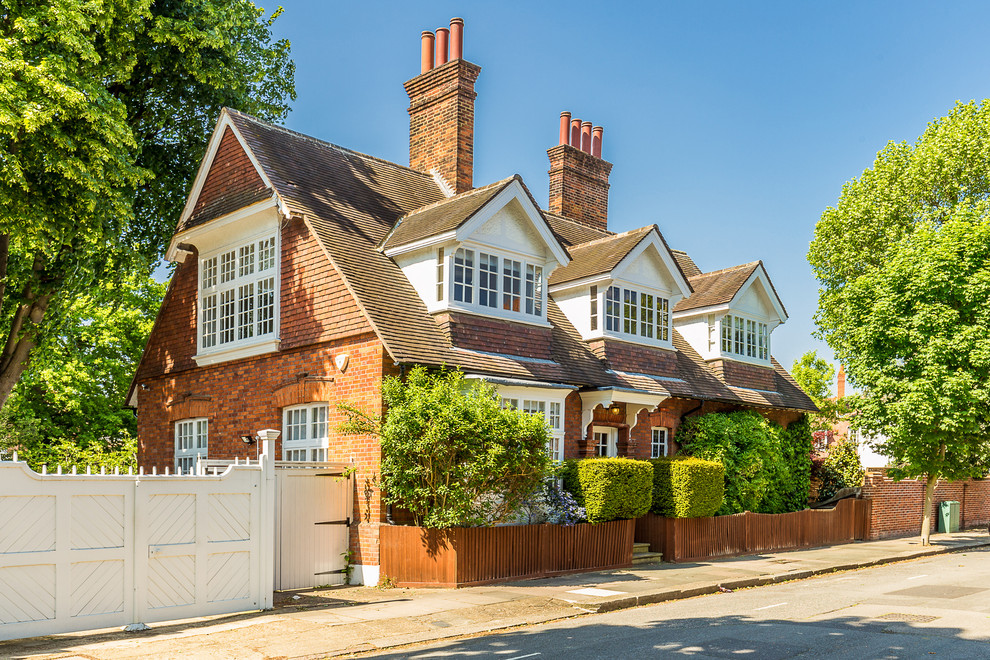 Red classic brick detached house in London with a shingle roof.