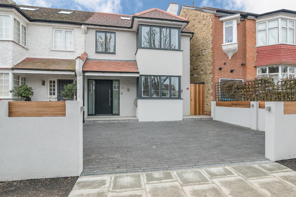 This is an example of a medium sized modern render semi-detached house in London with three floors, a flat roof and a mixed material roof.
