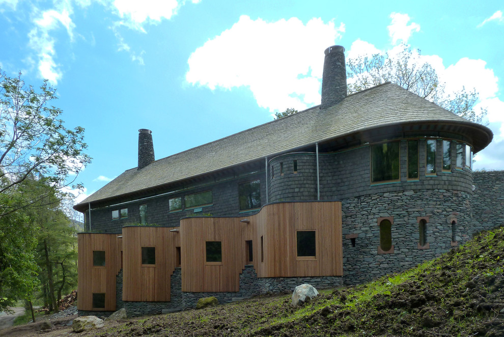 Cette image montre une très grande façade de maison grise design en pierre à deux étages et plus.