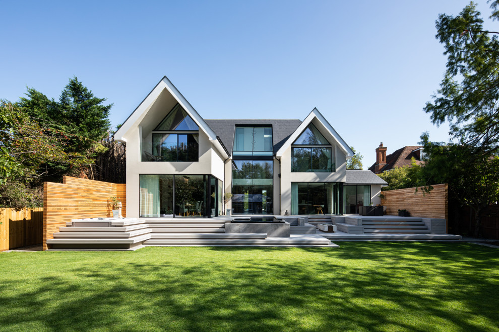 Photo of a white contemporary two floor detached house in Surrey with a pitched roof and a grey roof.