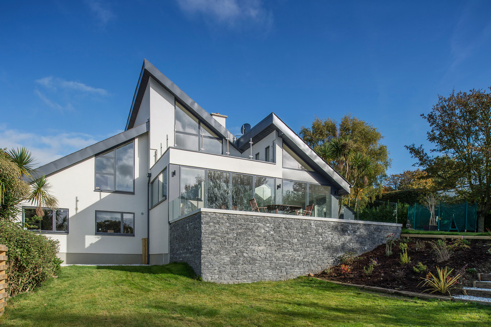 Large and white contemporary split-level house exterior in Dublin with mixed cladding and a flat roof.