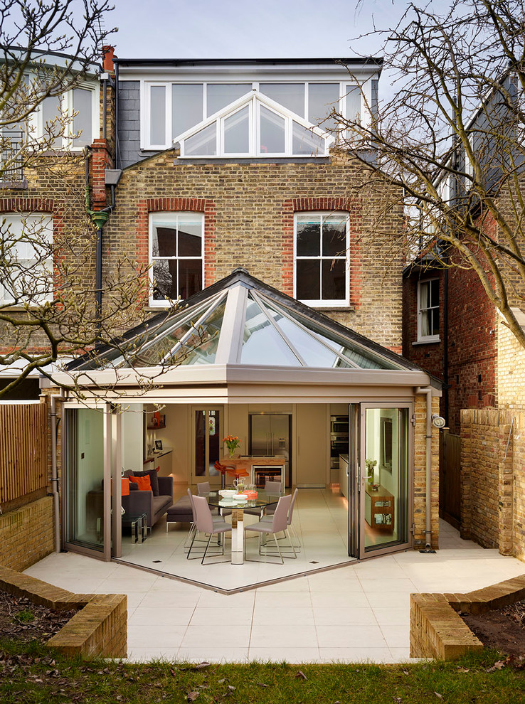 This is an example of a large and brown contemporary brick house exterior in London with three floors.