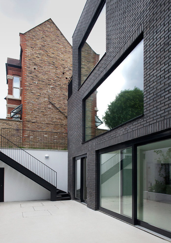 Réalisation d'une façade de maison noire minimaliste en brique avec un toit plat.