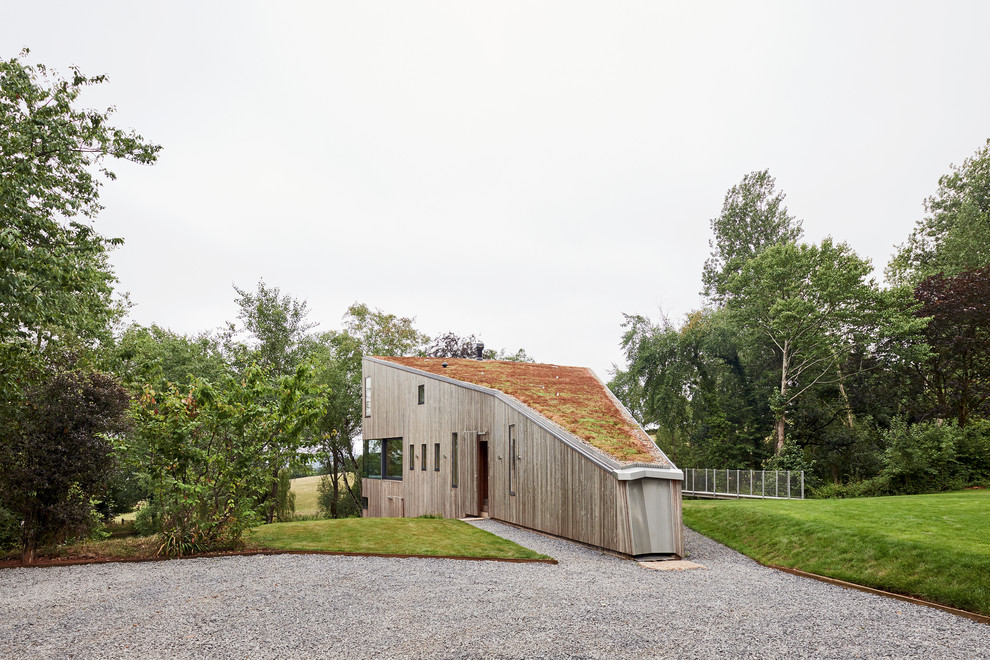 Diseño de fachada de casa marrón rural de tres plantas con revestimiento de madera, techo verde y tejado plano