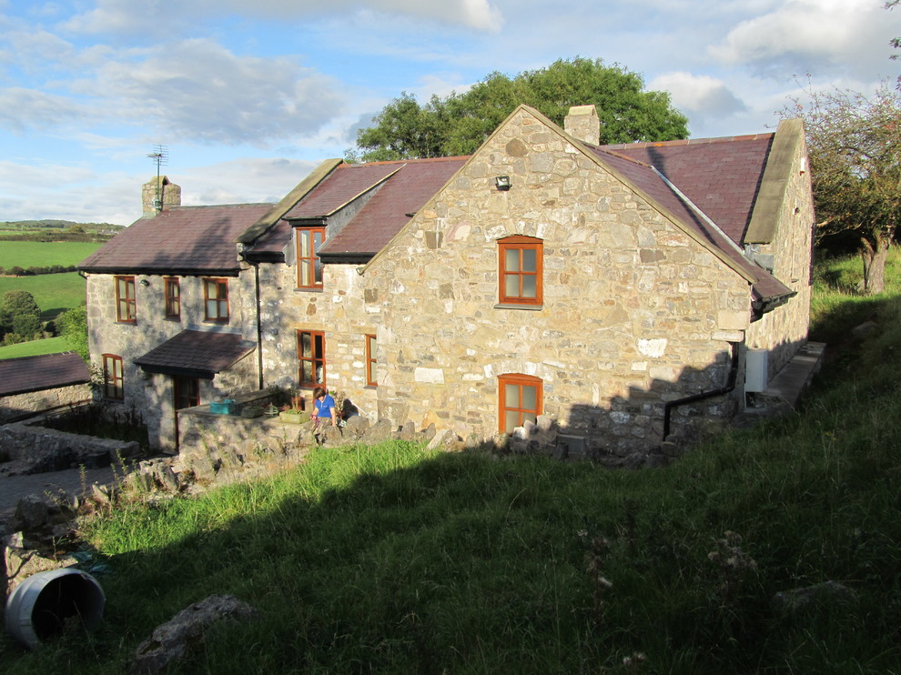 This is an example of a large and brown rural split-level house exterior in Other with stone cladding and a pitched roof.