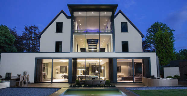 Inspiration pour une grande façade de maison beige minimaliste en stuc à deux étages et plus avec un toit à deux pans et un toit en tuile.