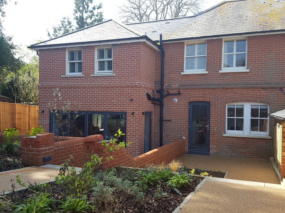 This is an example of a medium sized and red traditional brick semi-detached house in Hampshire with three floors, a pitched roof and a tiled roof.