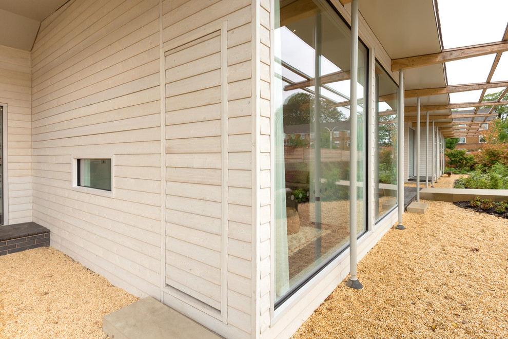 This is an example of a large and white contemporary bungalow house exterior in Cheshire with wood cladding.