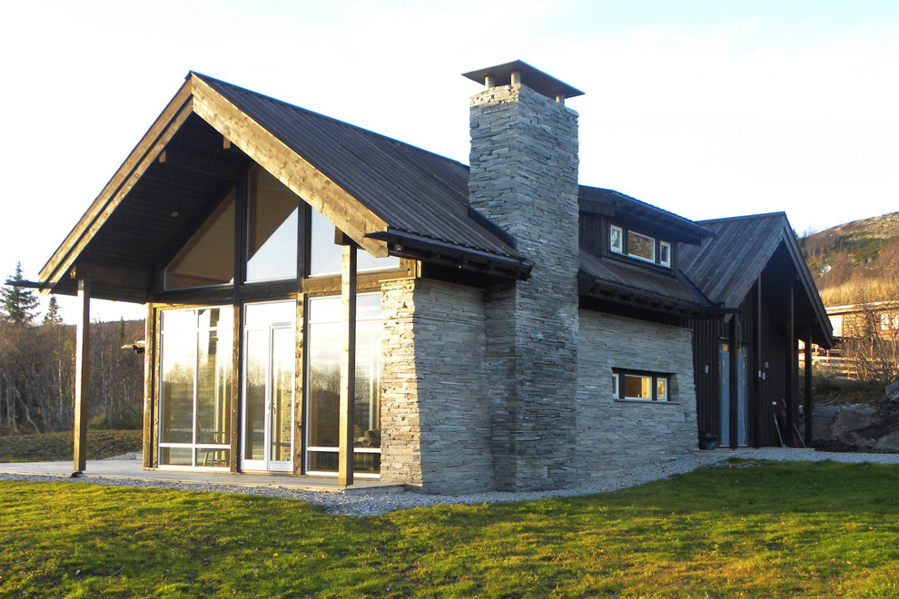 Cette image montre une façade de maison noire design en pierre de taille moyenne et à un étage avec un toit à deux pans.